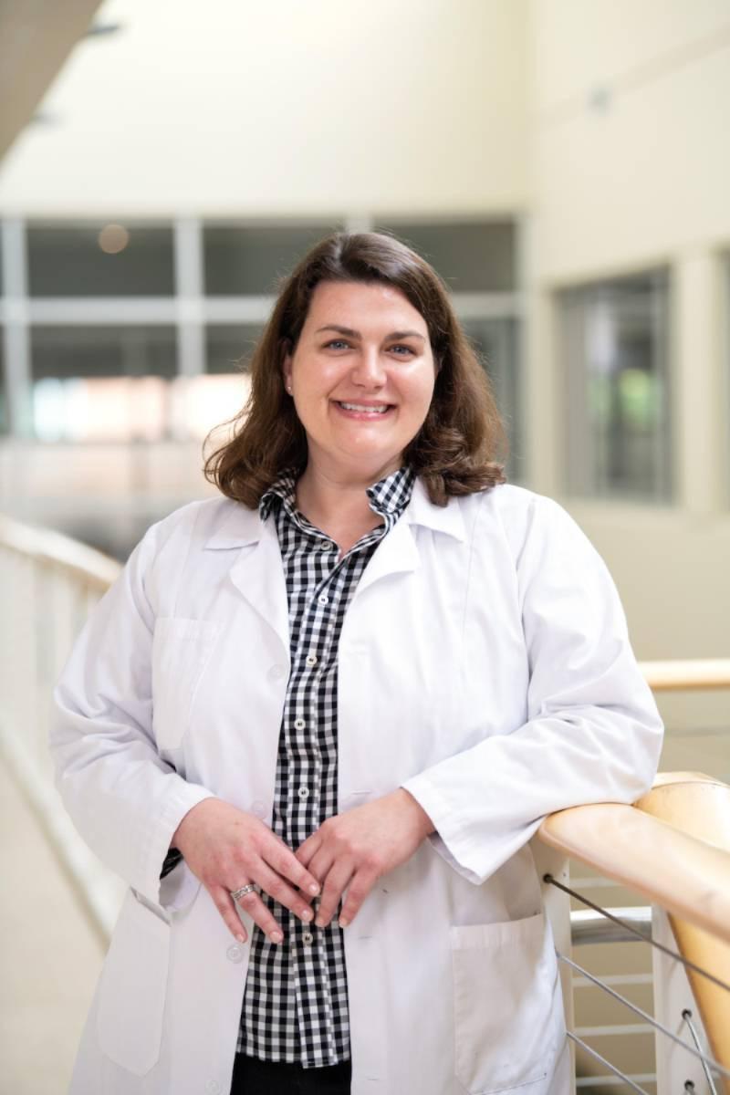 A nurse smiling at the camera in her white coat.